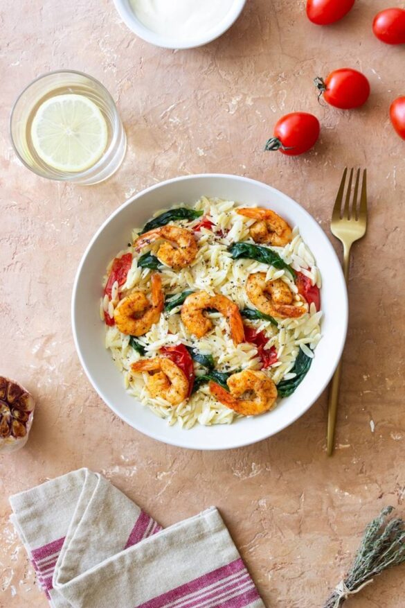 Orzo pasta with shrimp, spinach and tomatoes. Italian Cuisine. Seafood
